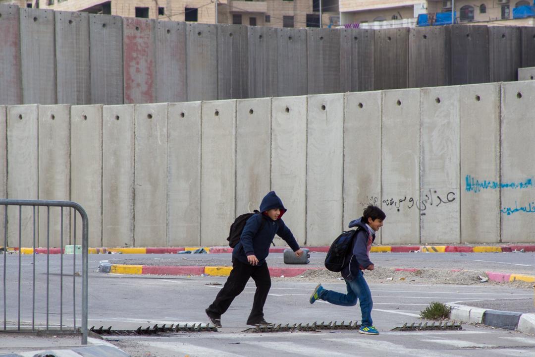 Familia caminando junto a un graffiti en Cisjordania