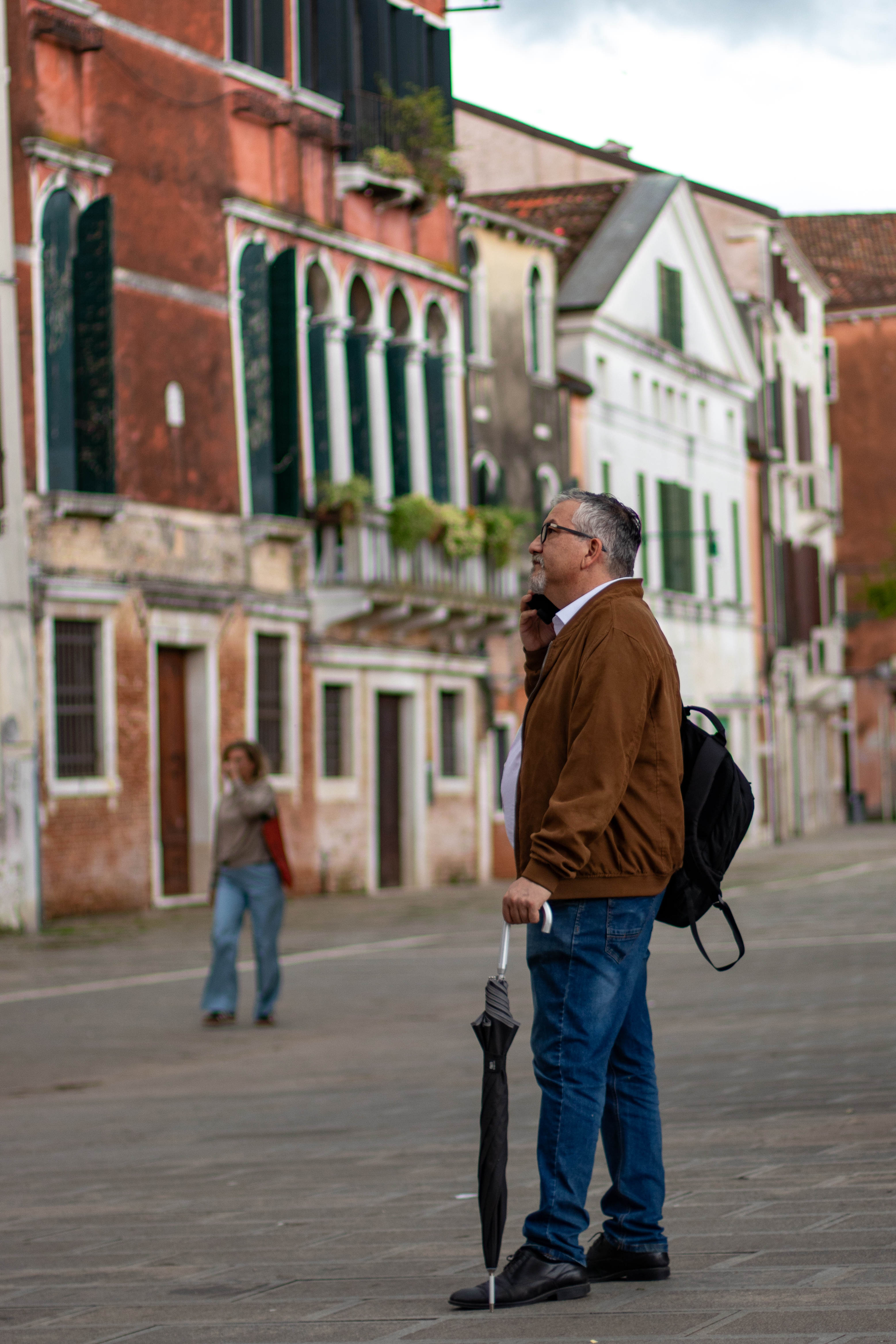 Hombre con paraguas mirando hacia una ventana en una calle de Venecia