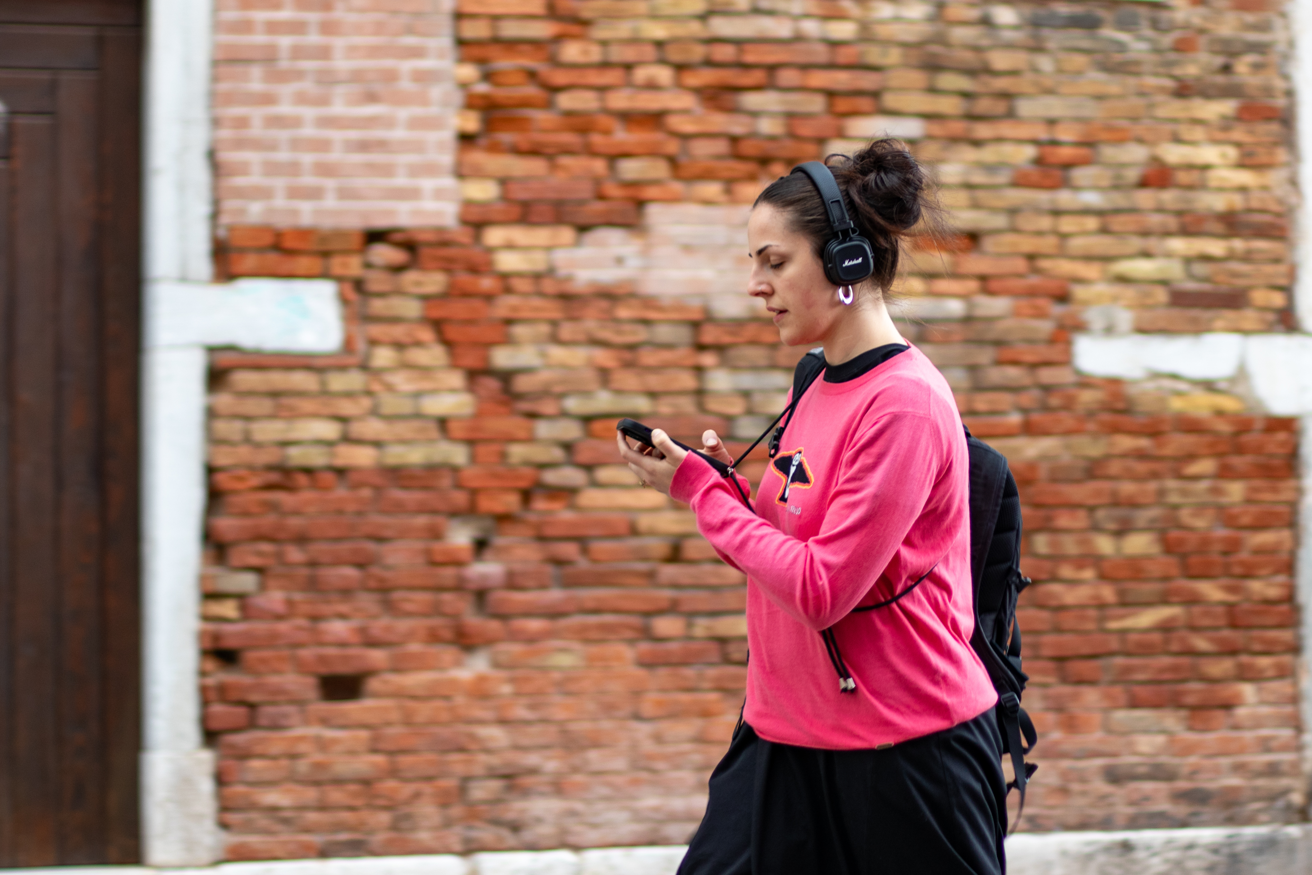 Mujer joven parada en la calle mirándose en la pantalla del móvil, Venecia