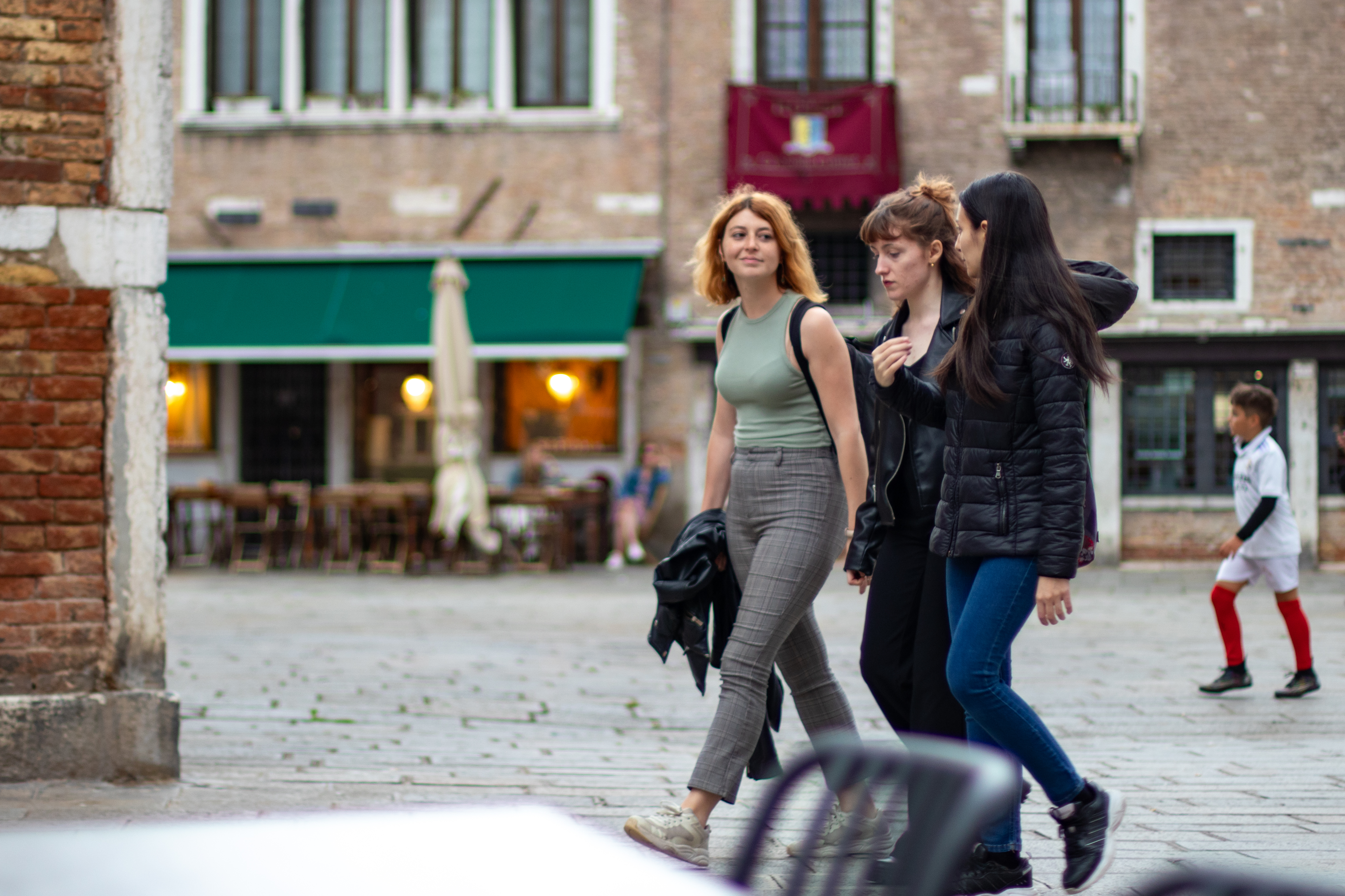 Tres chicas jóvenes caminando juntas por una calle de Venecia