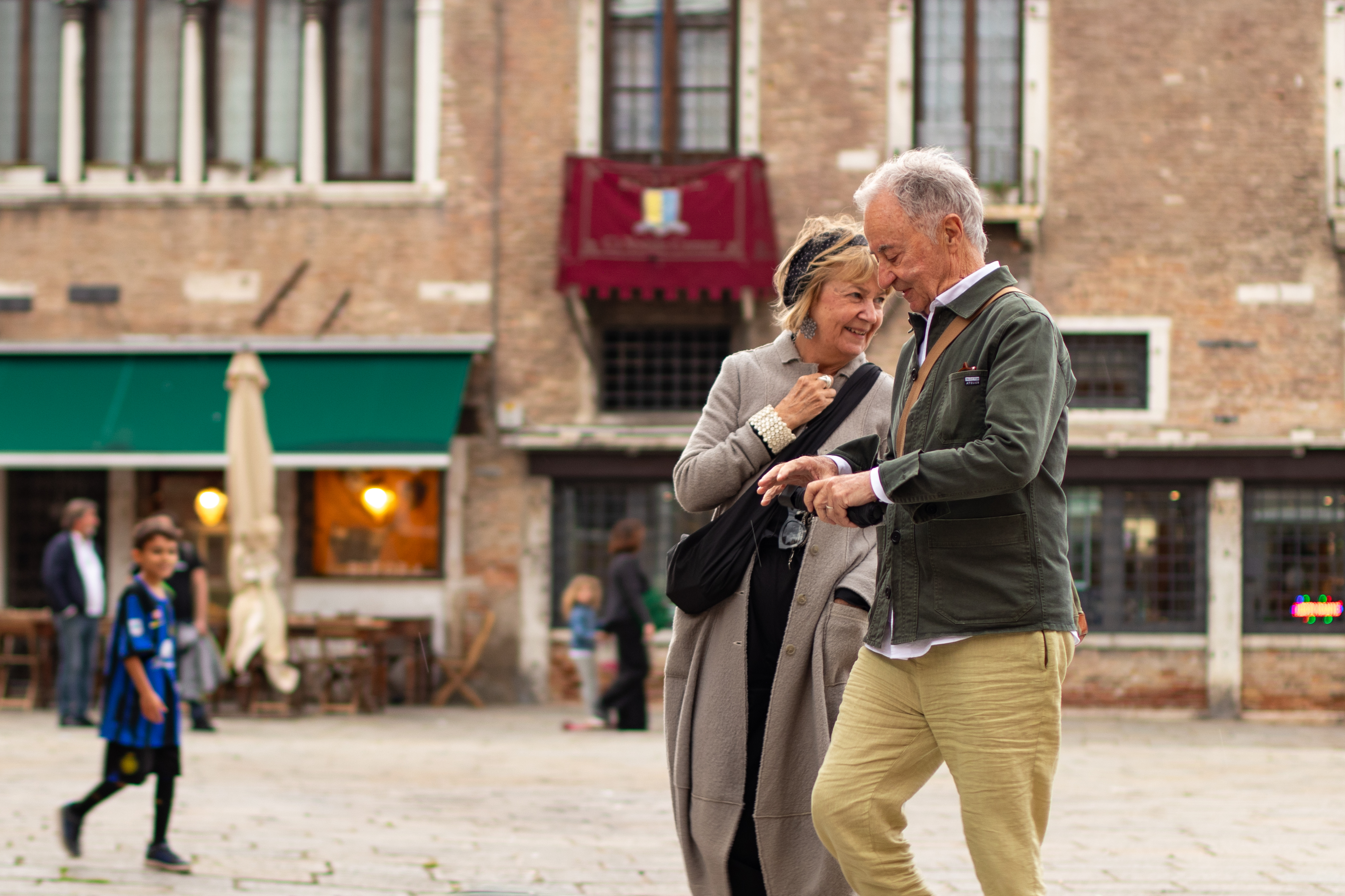 Pareja mayor caminando del brazo por una calle de Venecia